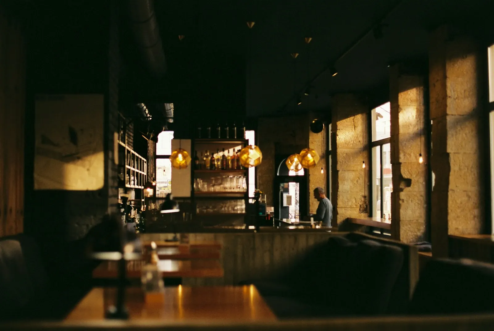 Low-lit dining room with wooden tables and warm pendant lights