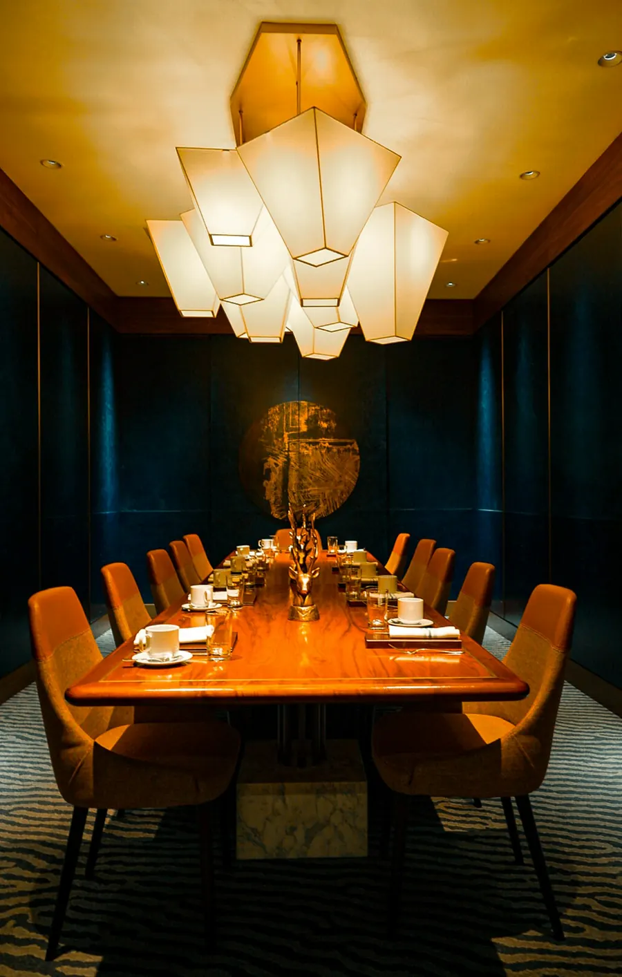 Private dining room with a long wooden table set for a group under warm paper lamps